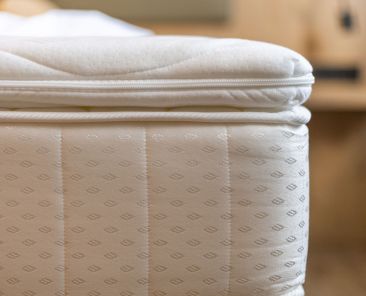 A well-crafted mattress is positioned neatly in a warm and inviting bedroom, showcasing its quilted fabric and attention to detail. A peaceful atmosphere promotes relaxation.