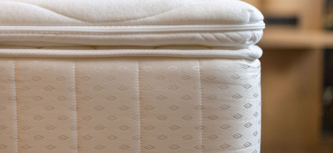 A well-crafted mattress is positioned neatly in a warm and inviting bedroom, showcasing its quilted fabric and attention to detail. A peaceful atmosphere promotes relaxation